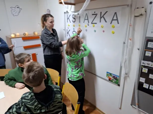 Uczennica układa wyraz "książka" z rozsypanki literowej.